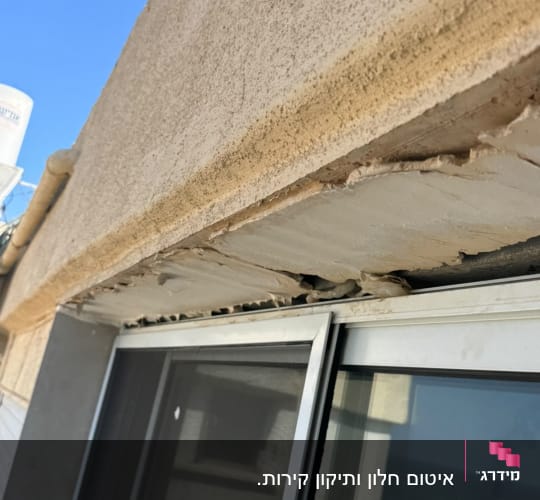 קיר חיצוני וארגז חלון עם טיח מרוסק ומתקלף הדורש תיקון